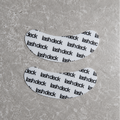 Two white eye patches with 'lash deck' text on a gray surface